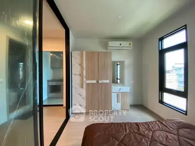 Modern bedroom with large windows and built-in wardrobe, featuring a sleek air conditioning unit.