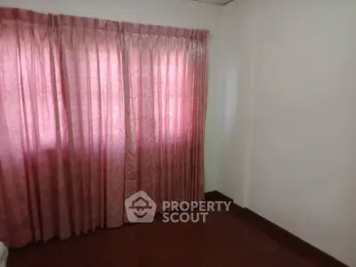 Cozy room with elegant pink curtains and wooden flooring, perfect for a serene living space.