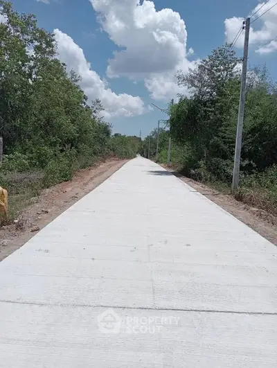 Scenic view of a newly paved road surrounded by lush greenery and clear blue sky.