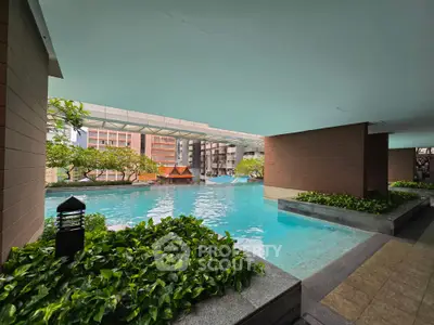 Luxurious condominium pool area with lush greenery and modern architecture, perfect for relaxation and leisure.
