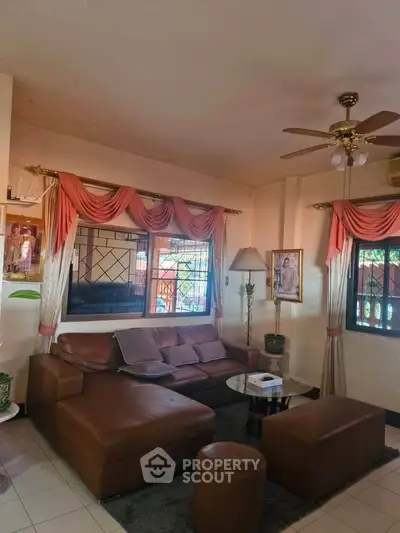 Cozy living room with elegant drapes and leather sofa, perfect for relaxation.