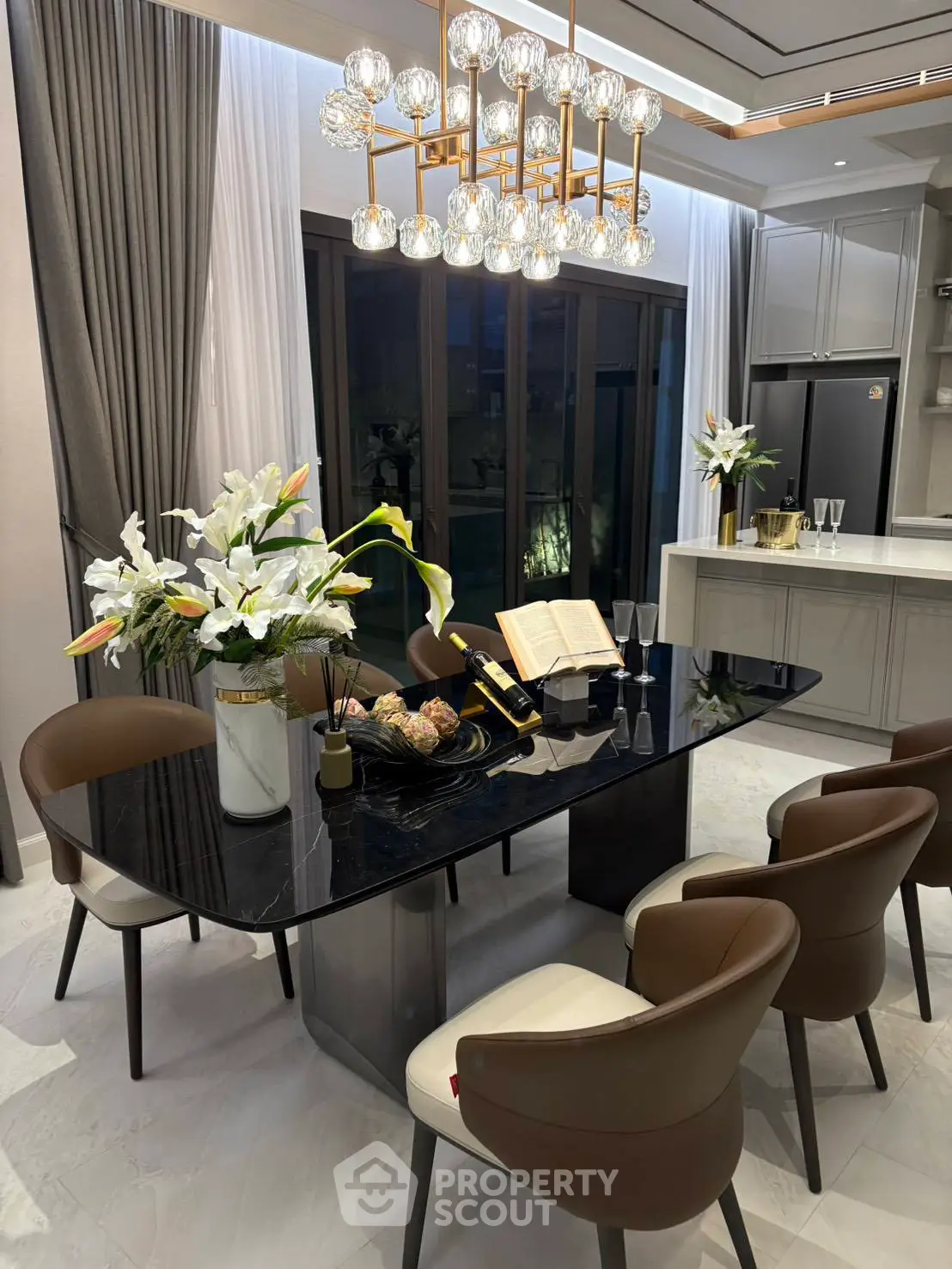 Luxurious dining area with elegant chandelier and modern kitchen, perfect for entertaining guests.