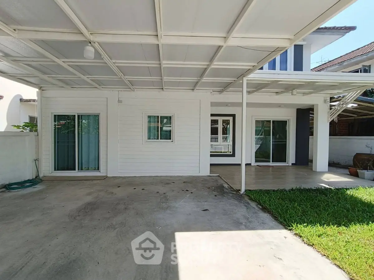 Spacious covered patio area with sliding glass doors and adjacent lawn, perfect for outdoor relaxation.
