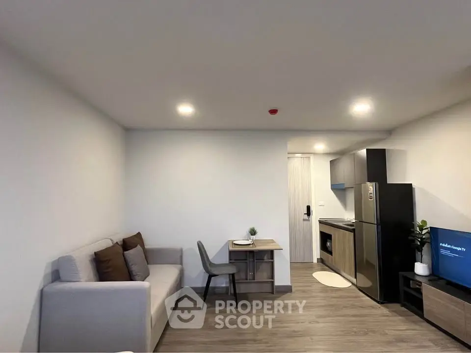 Modern living room with cozy sofa and compact kitchen area in stylish apartment.
