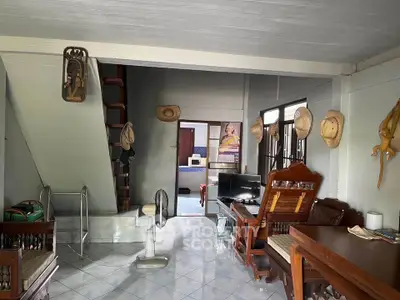 Charming living room with rustic decor and staircase, featuring traditional wooden furniture and tiled flooring.