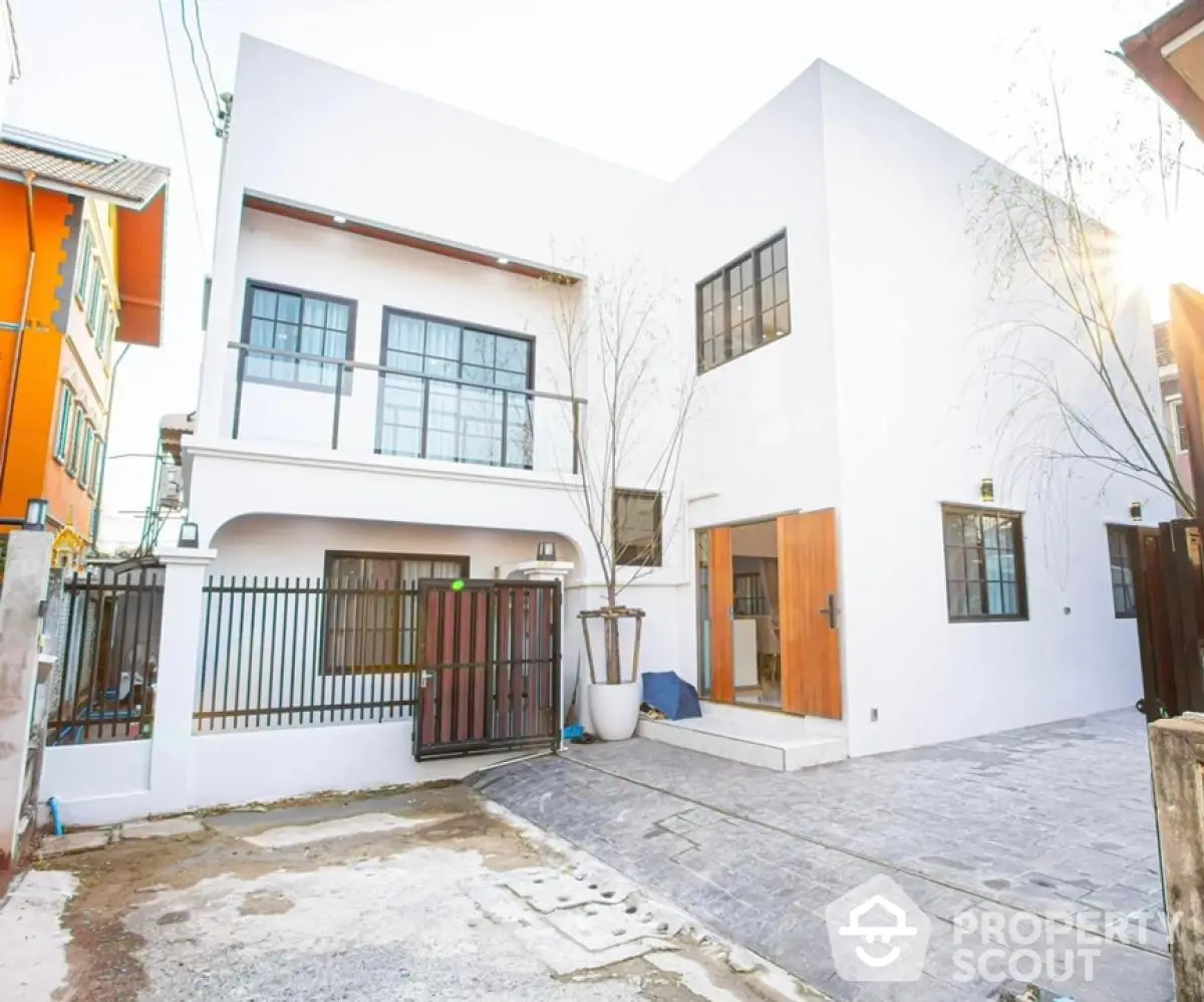 Modern minimalist white house exterior with gated entrance and driveway