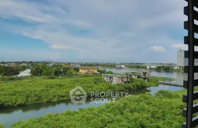 Stunning panoramic view of lush greenery and serene waterway from a high-rise balcony.