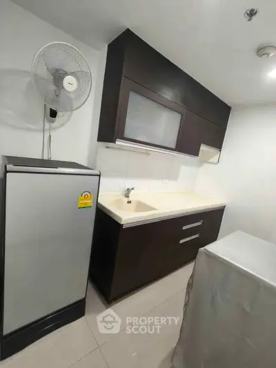 Modern kitchen with sleek cabinetry and compact fridge in a stylish apartment.