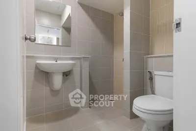 Modern bathroom with sleek fixtures and neutral tiles, featuring a shower and toilet.