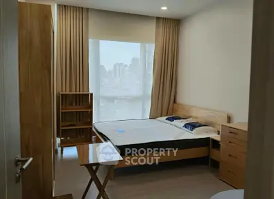 Modern bedroom with city view, wooden furniture, and natural light.