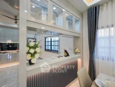 Elegant dining area with modern decor and open kitchen layout, featuring stylish lighting and floral accents.
