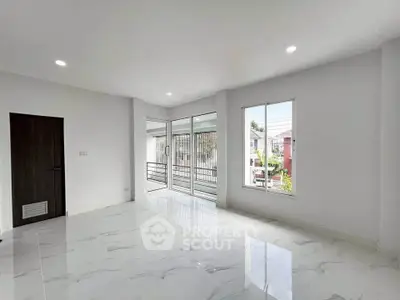 Spacious modern living room with large windows and balcony access, featuring sleek white marble flooring.