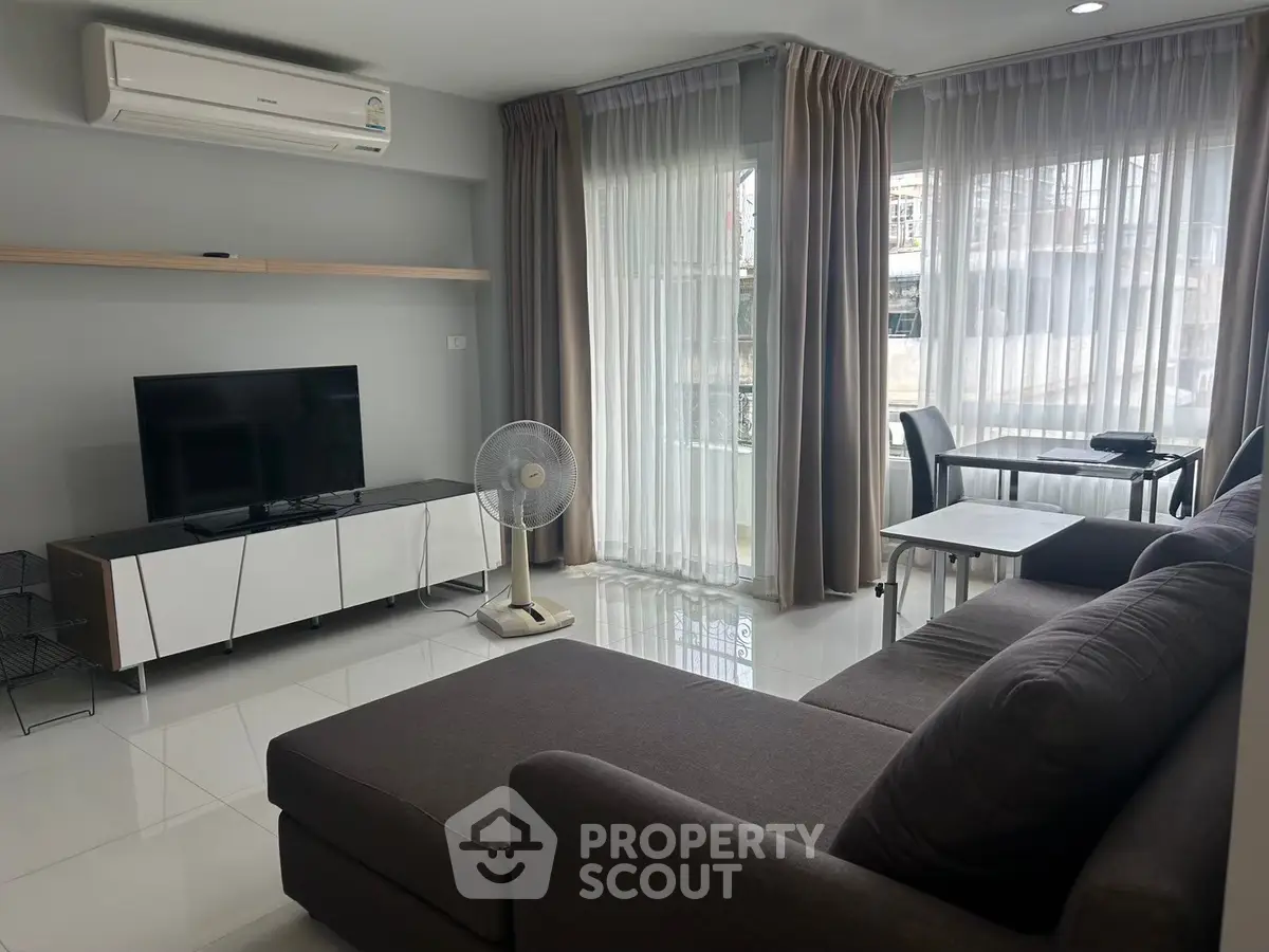 Modern living room with sleek furniture and natural light, featuring a cozy sofa and entertainment setup.