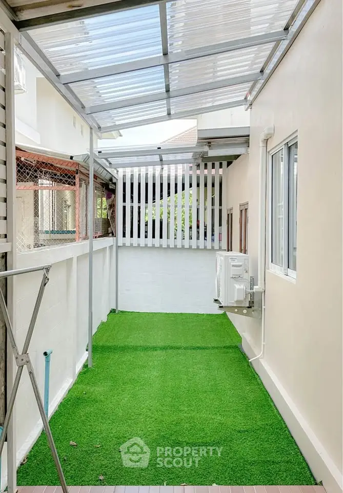 Charming outdoor space with artificial grass and covered roof, perfect for relaxation or small gatherings.