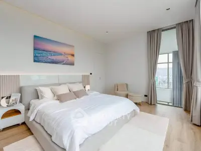 Luxurious bedroom with elegant decor and large windows offering natural light and serene views.