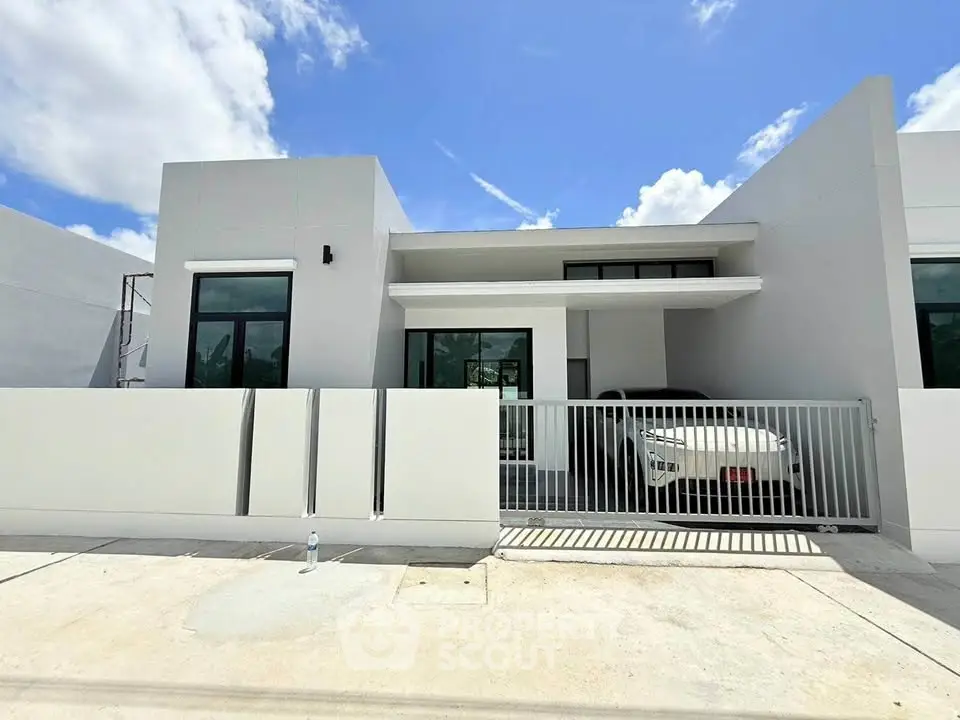 Modern minimalist house exterior with sleek design and carport under clear blue sky.