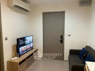 Cozy living room with modern TV setup and comfortable seating in a compact apartment.