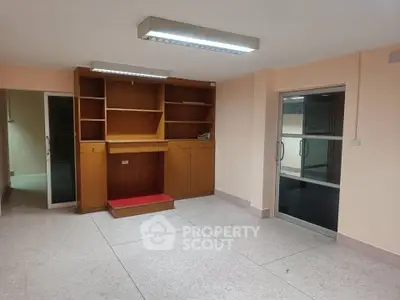 Spacious room with built-in wooden shelves and sliding glass doors, ideal for office or study space.