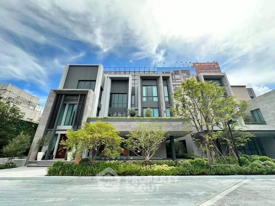 Modern multi-story building with lush landscaping and contemporary design elements.