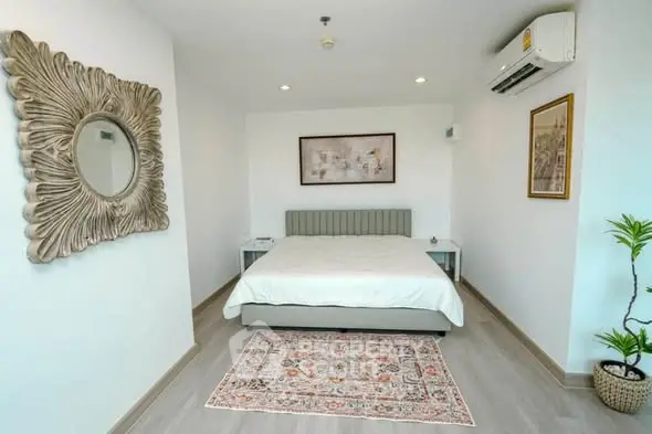 Modern bedroom with stylish decor, featuring a large mirror, elegant artwork, and a cozy bed.