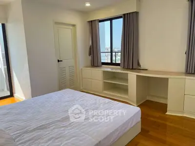 Bright bedroom with large windows and modern furnishings in a high-rise apartment.