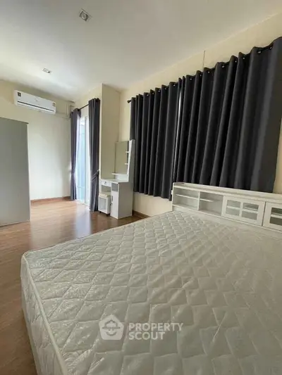 Spacious bedroom with modern furnishings and large windows for natural light.