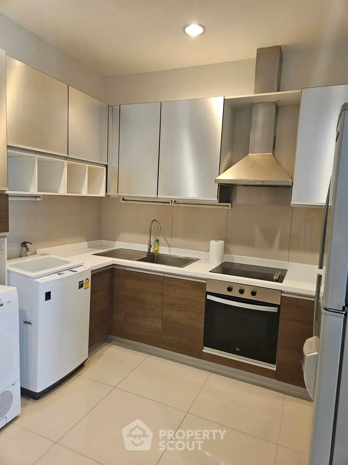 Modern kitchen with sleek cabinetry, built-in oven, and washing machine in a contemporary apartment.