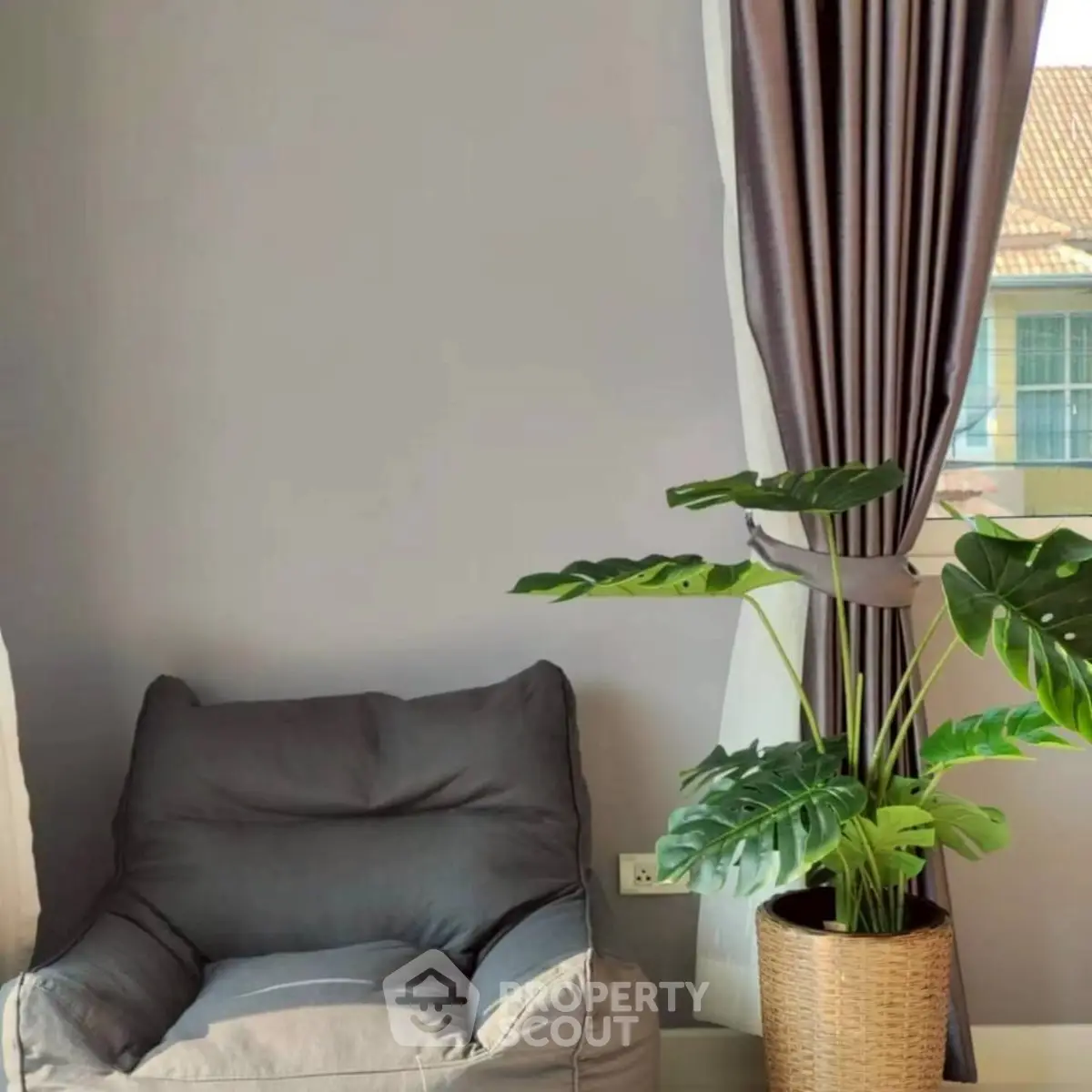 Cozy living room corner with plush chair and potted plant by window