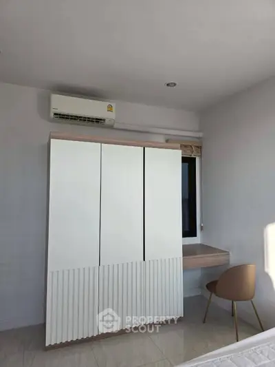Modern bedroom with sleek wardrobe and compact study area under natural light.
