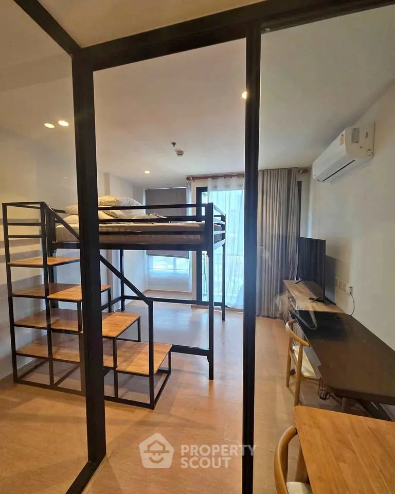 Modern studio apartment with loft bed and workspace, featuring sleek design and natural light.