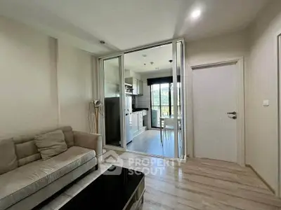 Modern living room with sliding glass doors leading to a bright kitchen and dining area.
