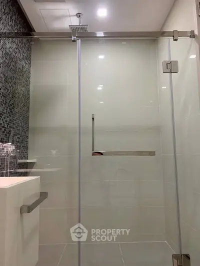 Modern bathroom with sleek glass shower door and stylish tile design.