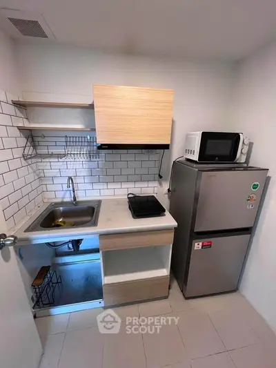 Compact modern kitchen with fridge, microwave, and electric stove in a cozy apartment.