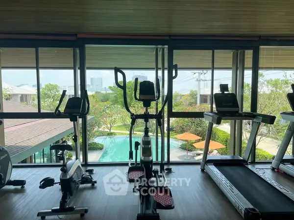 Modern gym with pool view and exercise equipment in luxury real estate property.