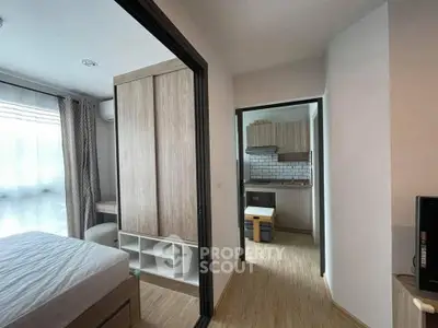 Modern apartment interior with bedroom and kitchen, featuring wooden flooring and stylish furnishings.