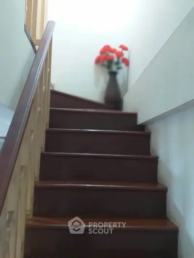 Elegant staircase with wooden steps and decorative vase in a cozy home setting.
