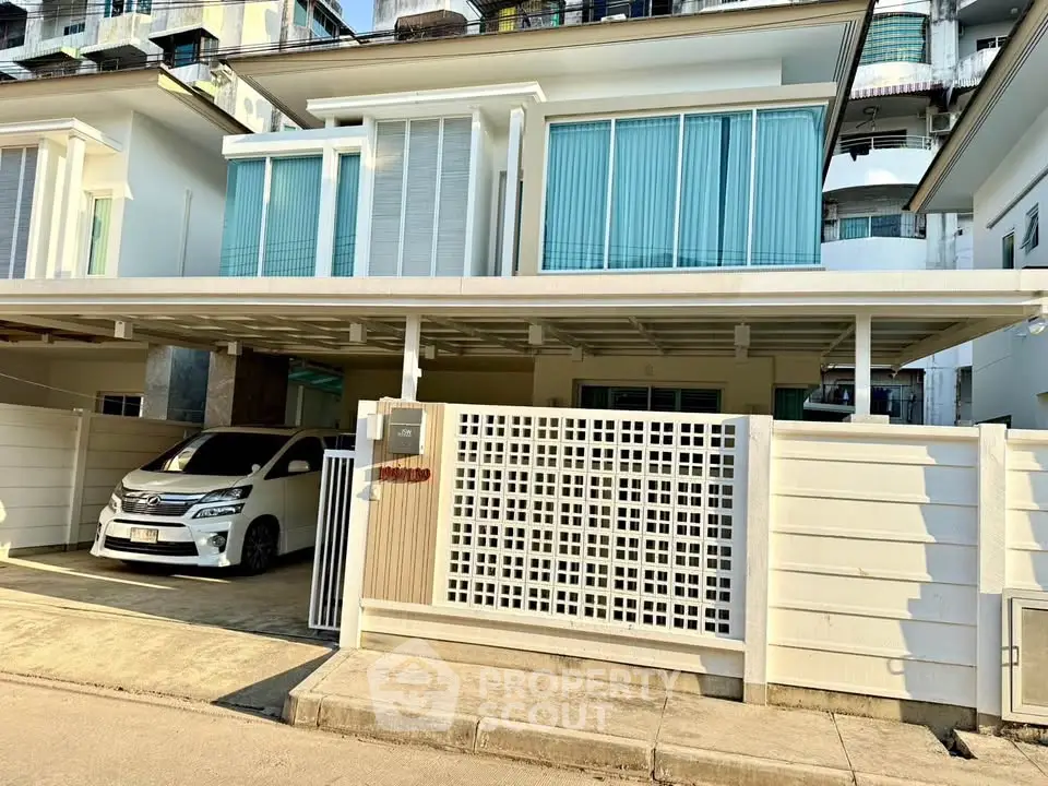 Modern two-story house with carport and sleek design in urban setting.