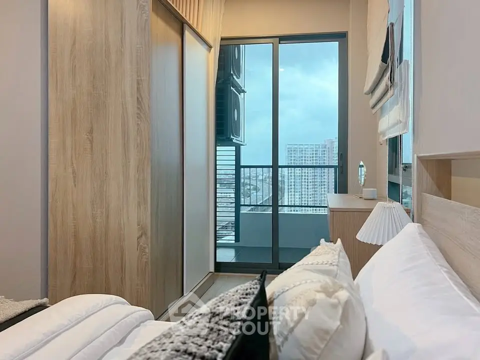 Modern bedroom with balcony view in high-rise apartment, featuring sleek design and natural light.