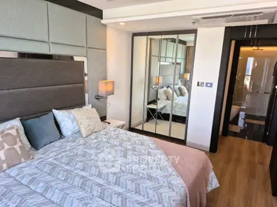 Luxurious bedroom with modern decor and mirrored wardrobe, adjacent to a sleek bathroom.