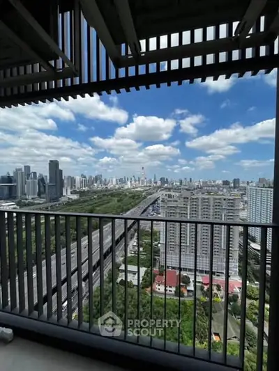 Stunning cityscape view from a high-rise balcony overlooking urban skyline and lush greenery.