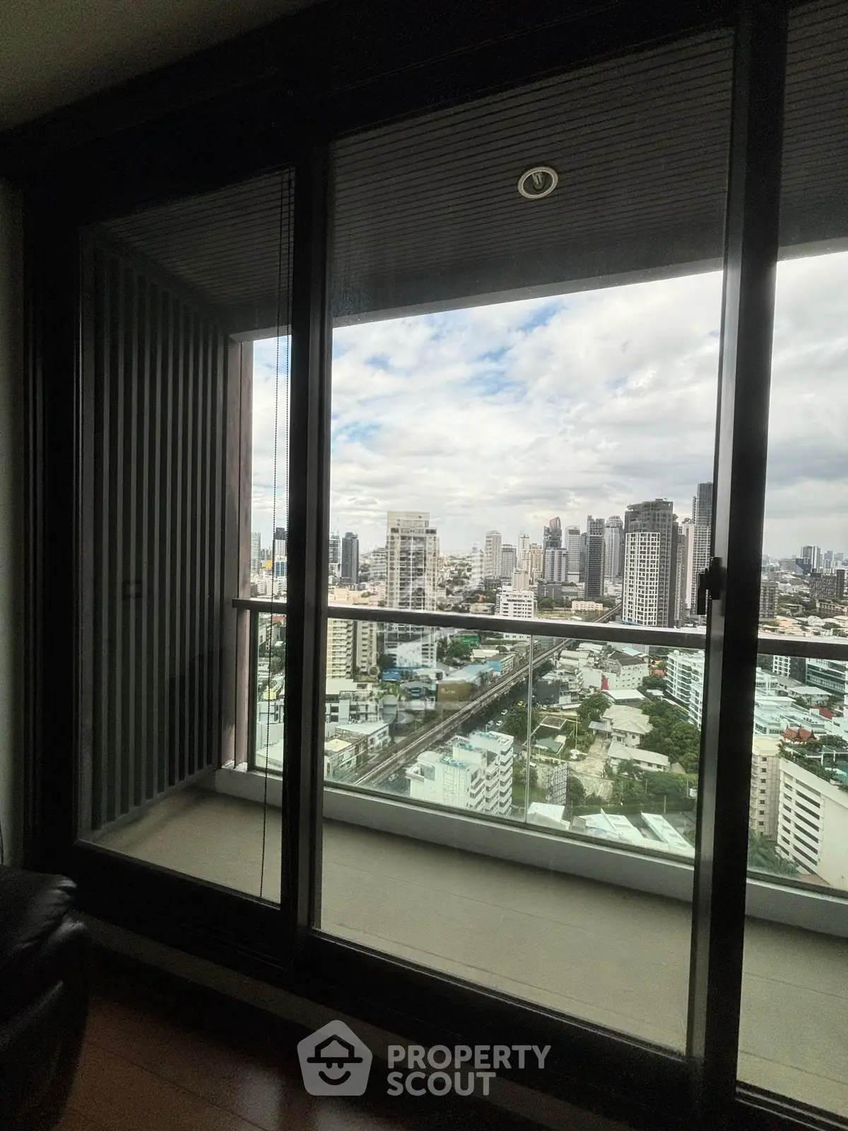 Stunning city view from high-rise apartment balcony with floor-to-ceiling windows.