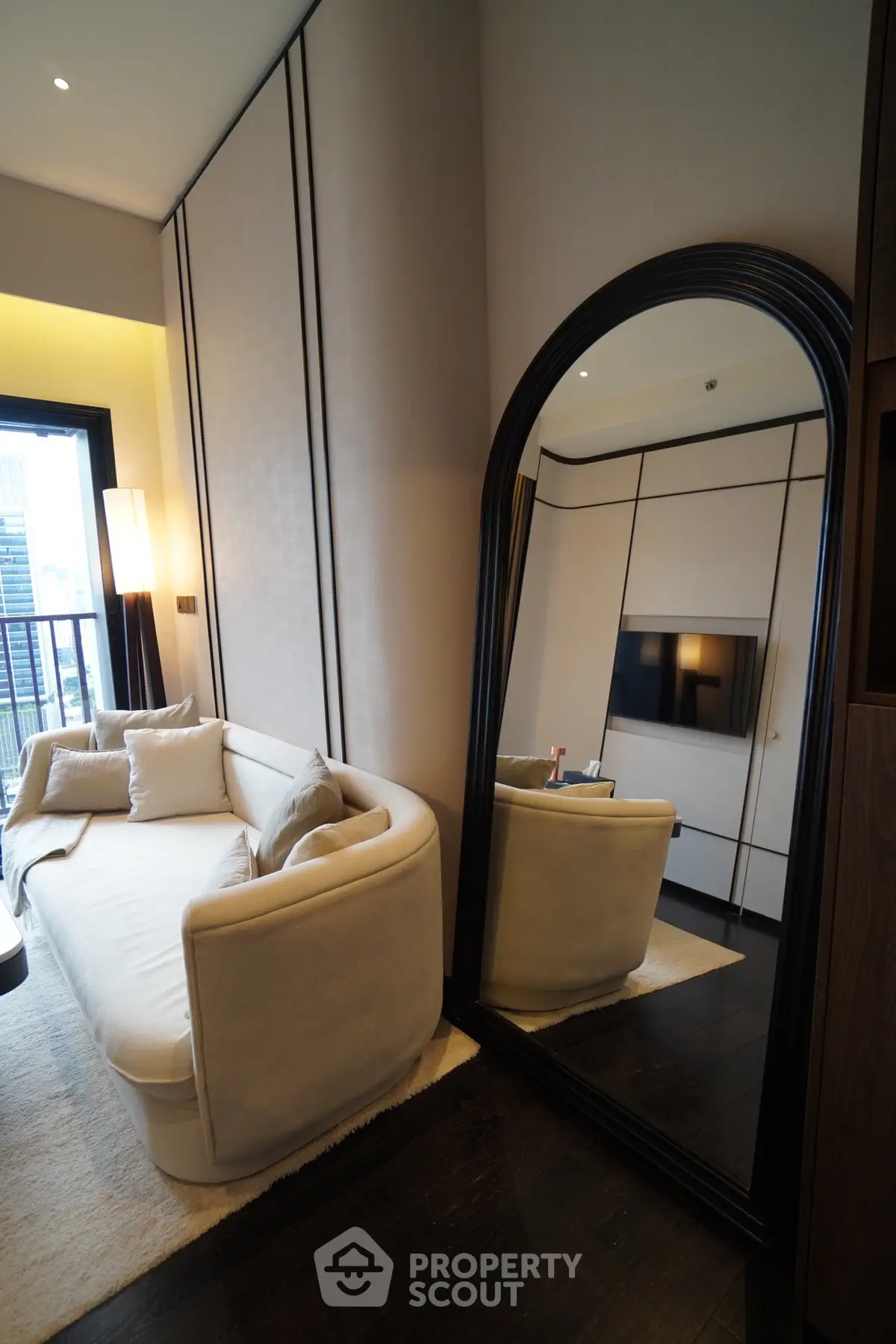 Luxurious living room with elegant sofa and large mirror, offering a glimpse of modern city living.