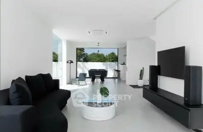 Modern minimalist living room with sleek black furniture and large windows offering natural light.