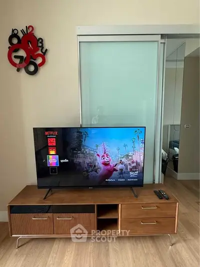 Modern living room with stylish TV stand and unique wall clock, featuring a sliding glass door.