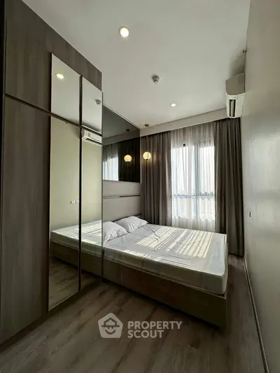 Modern bedroom with large mirror and natural light, featuring sleek design and cozy ambiance.