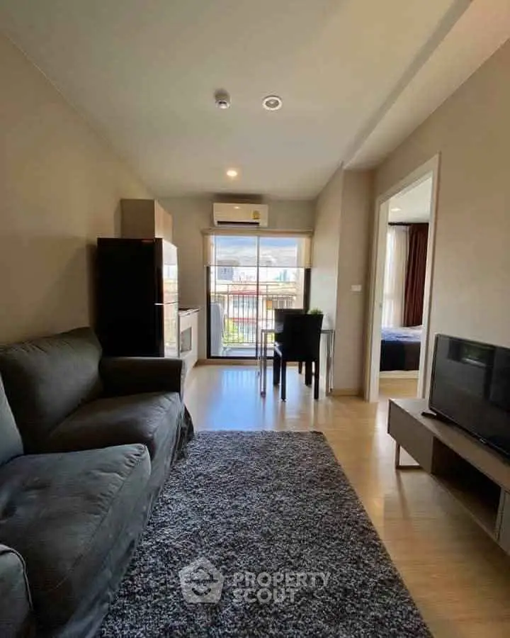 Modern living room with cozy sofa, TV, and dining area near balcony with natural light.