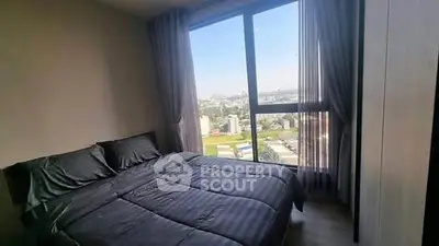 Modern bedroom with large window offering stunning city view and natural light.