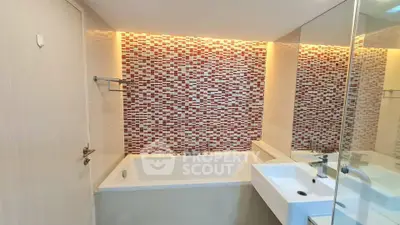 Modern bathroom with stylish mosaic tiles and built-in bathtub.