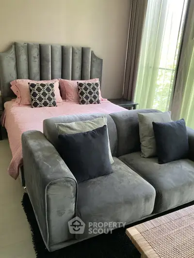 Luxurious bedroom with plush gray sofa and elegant bed, perfect for relaxation.