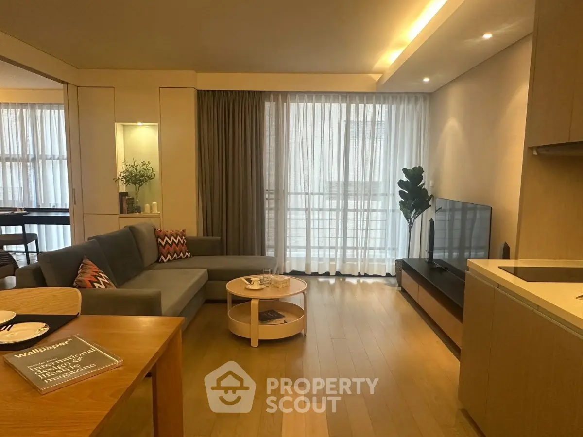 Modern living room with cozy sofa, stylish decor, and natural light from large windows.